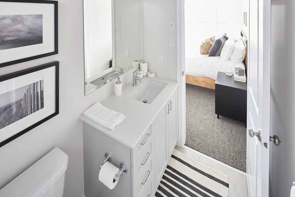 a bathroom with a sink and a mirror and a bedroom with a bed