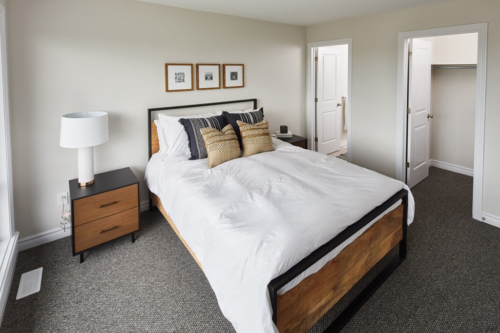 a bedroom with a bed and two nightstands and a door to a bathroom