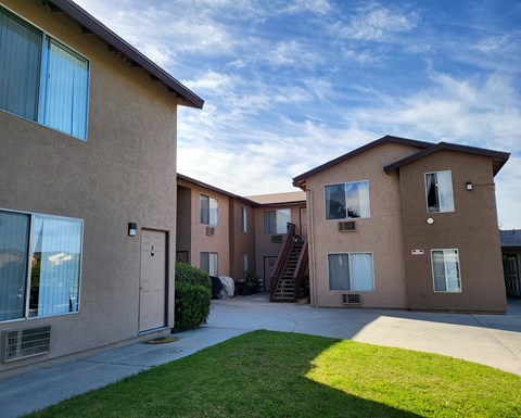 an apartment building with a sidewalk and grass