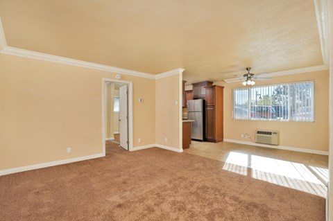 an empty living room with a ceiling fan and a kitchen