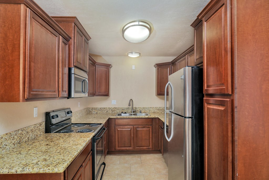 a kitchen with wood cabinets and granite counter tops and a stainless steel refrigerator