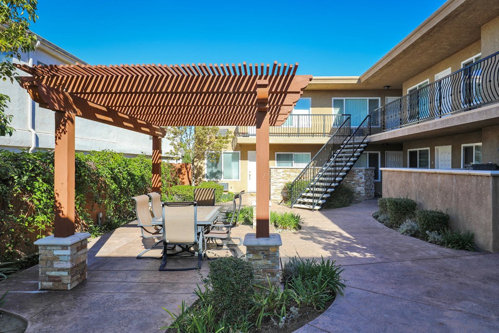 a patio with a table and chairs under a wooden pergola