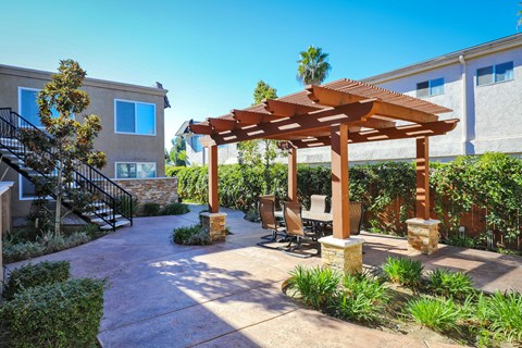 a patio with a wooden pavilion and a table and chairs