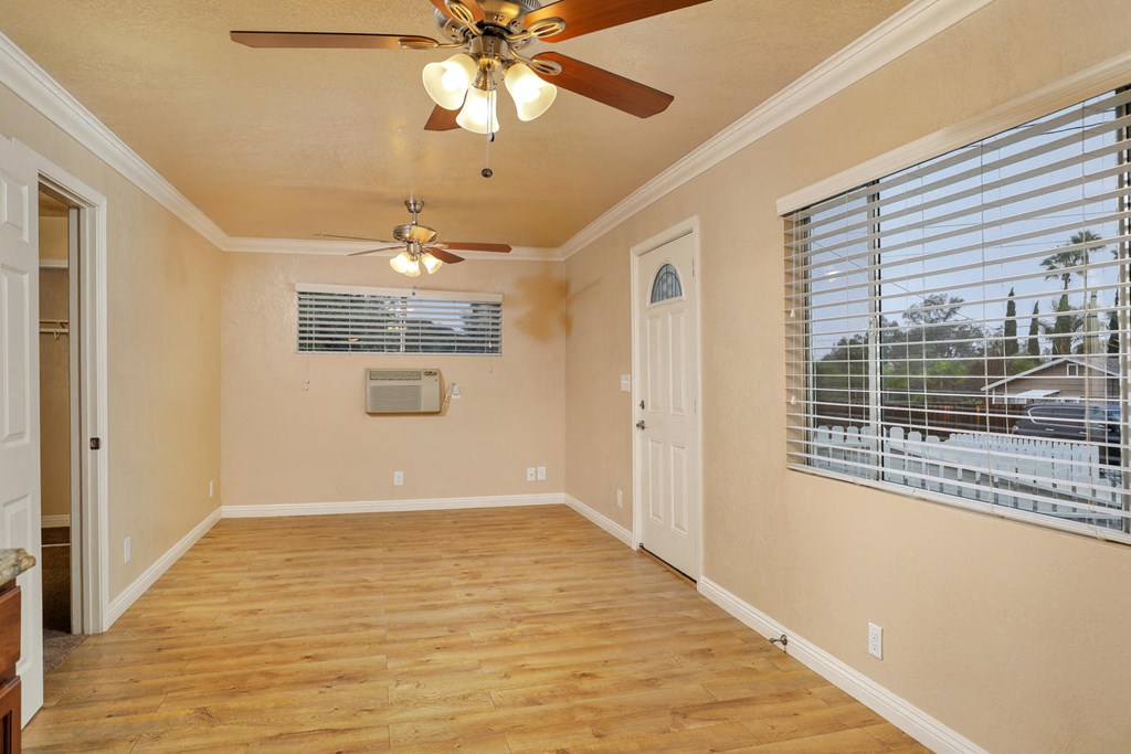 an empty living room with a ceiling fan and a window