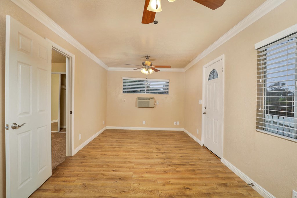 a empty living room with a ceiling fan and a door to a closet