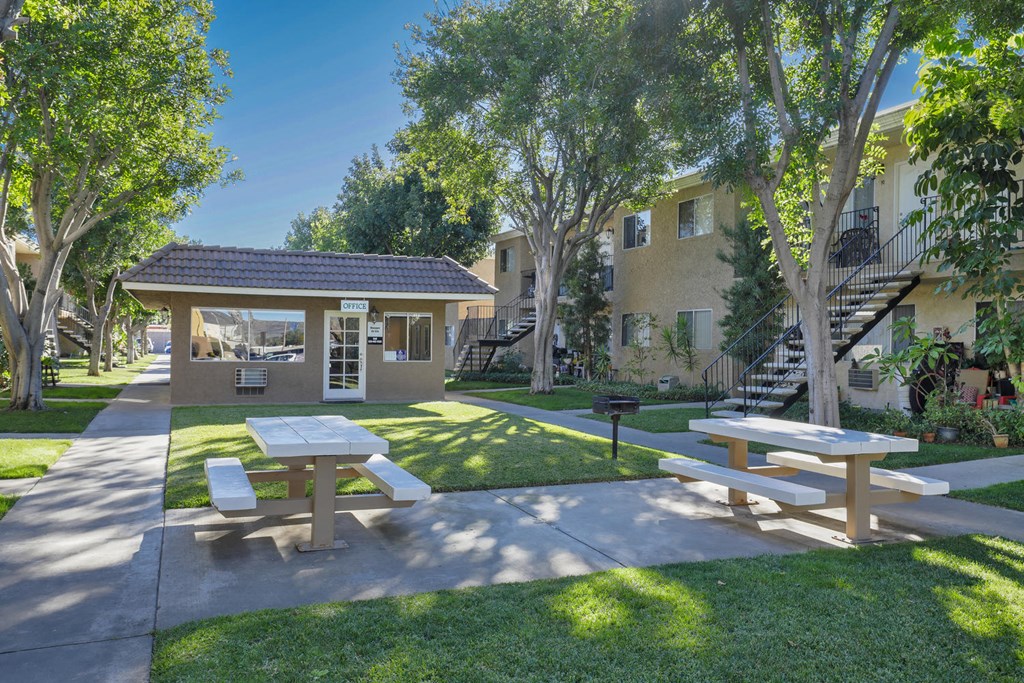 a picnic area with benches and picnic tables in front of a building