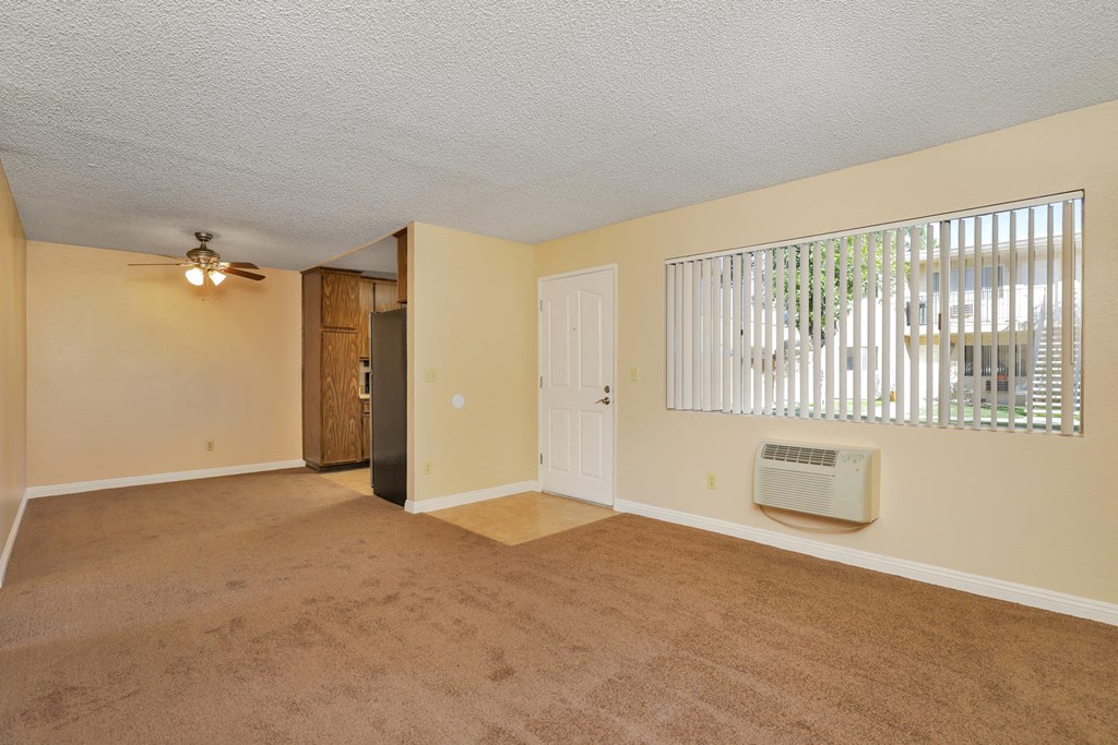 an empty living room with a window and a ceiling fan