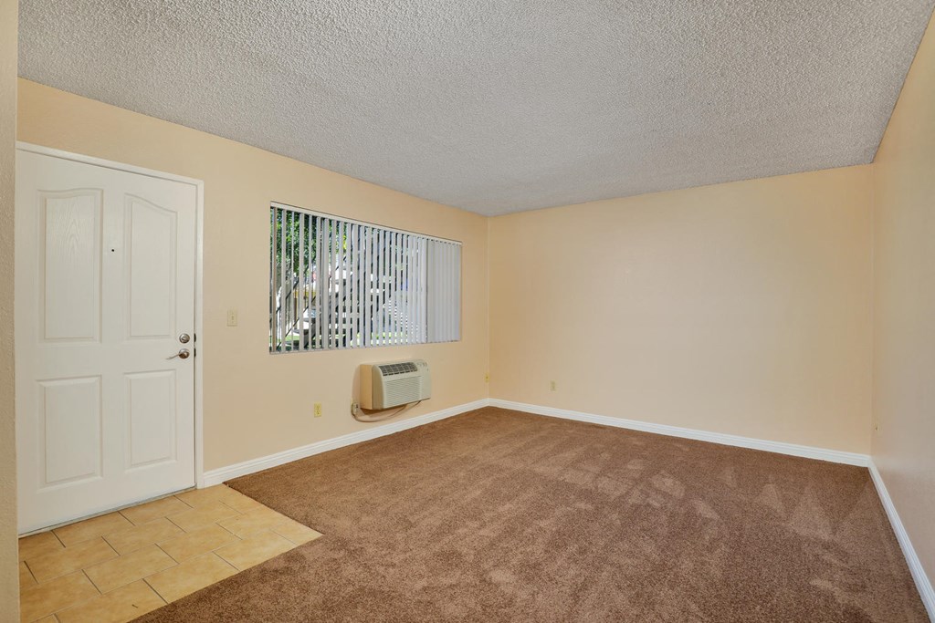 an empty living room with a white door and carpet