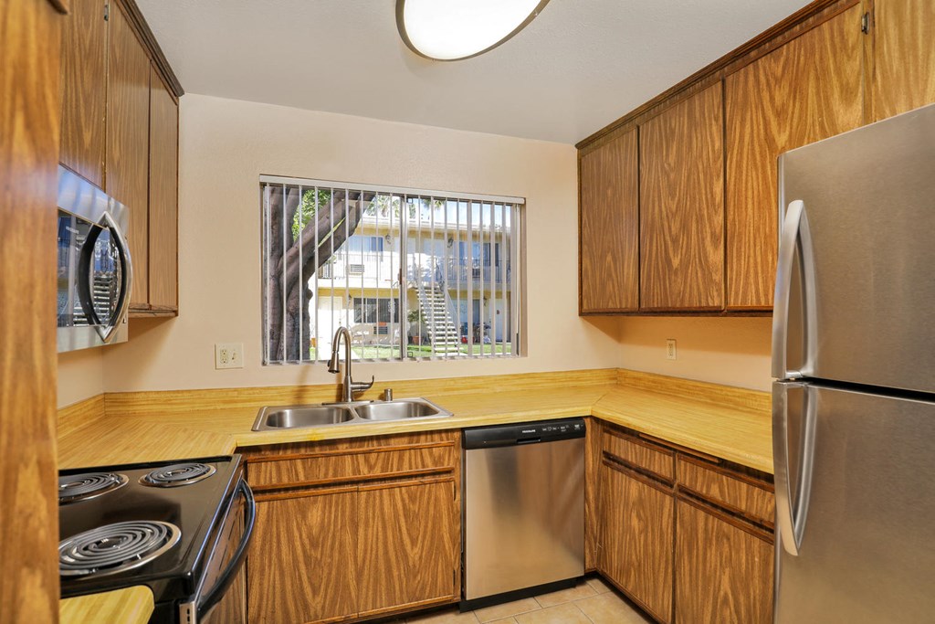 a kitchen with wooden cabinets and stainless steel appliances and a window
