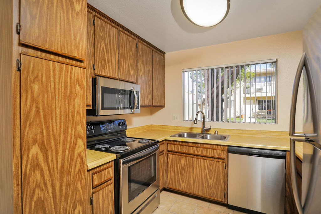a kitchen with wooden cabinets and appliances and a window