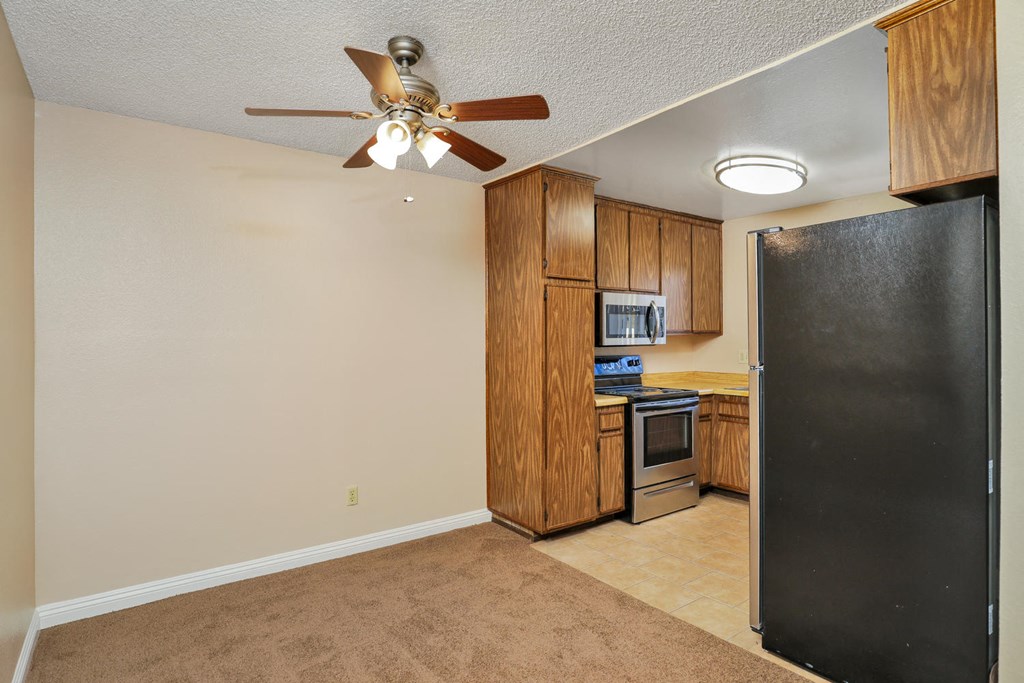 a kitchen with a ceiling fan and a black refrigerator