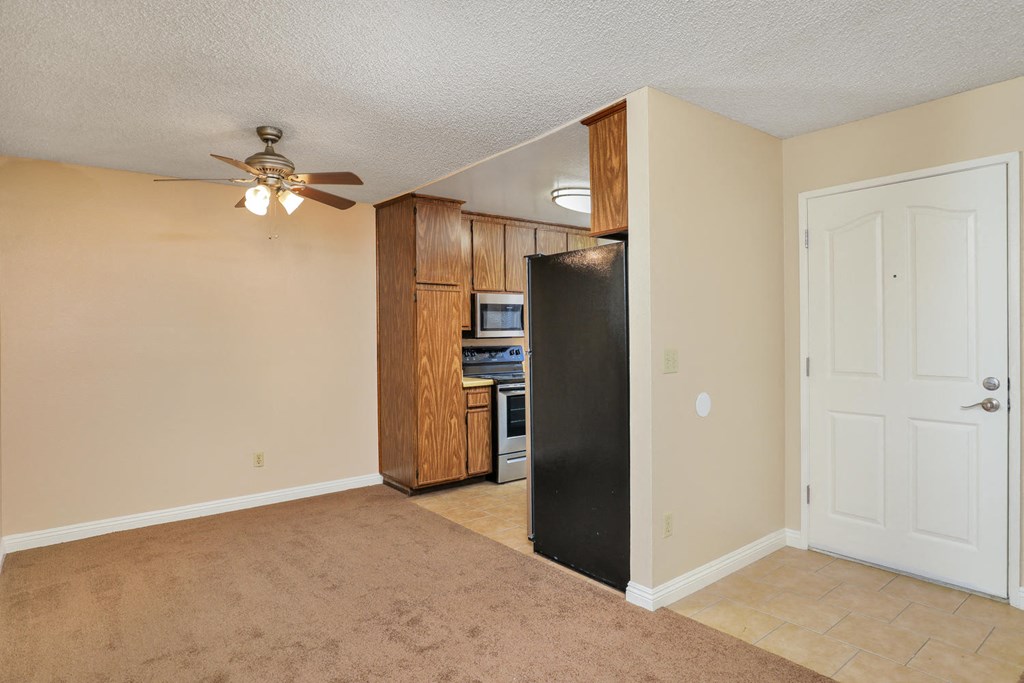 an empty kitchen with a refrigerator and a ceiling fan