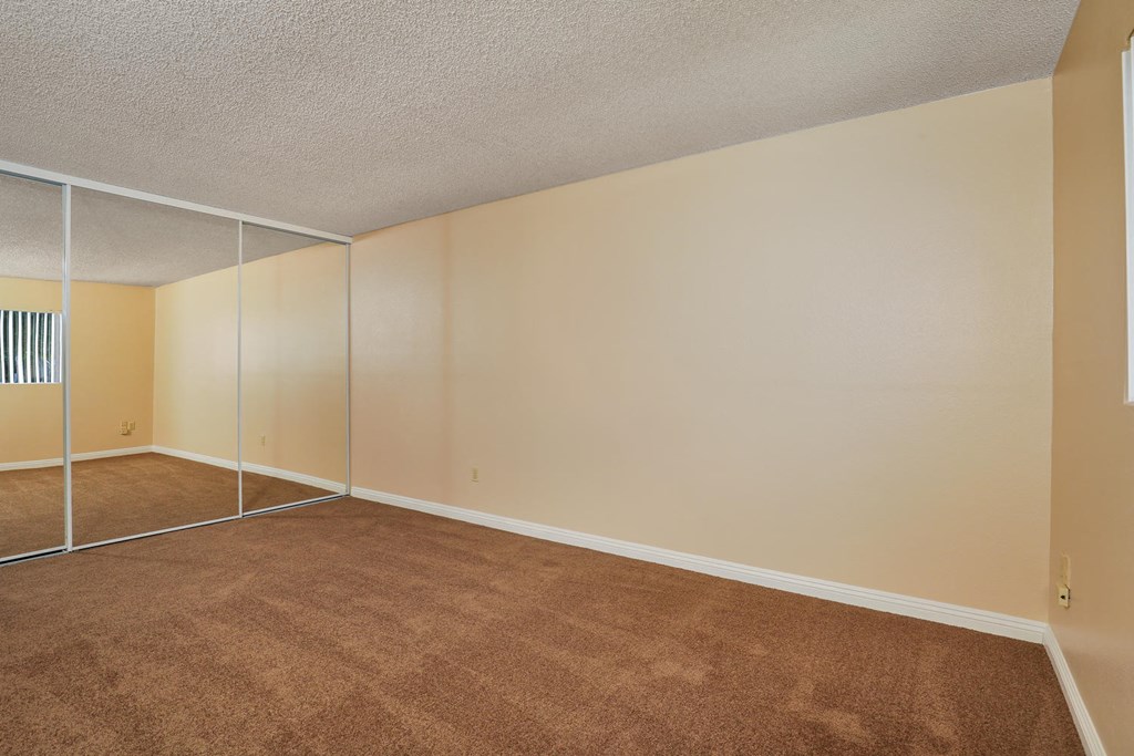 an empty living room with mirrored closet doors