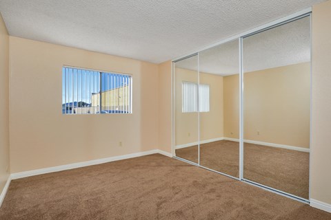 an empty bedroom with mirrored doors and carpeted flooring