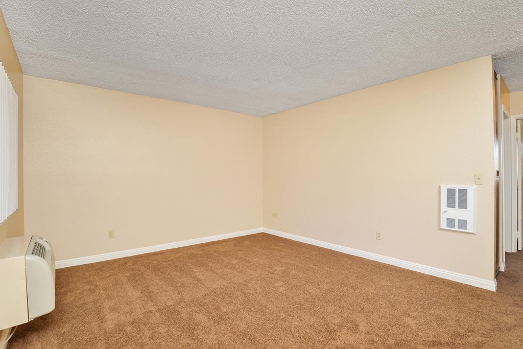 an empty living room with beige carpet and white walls