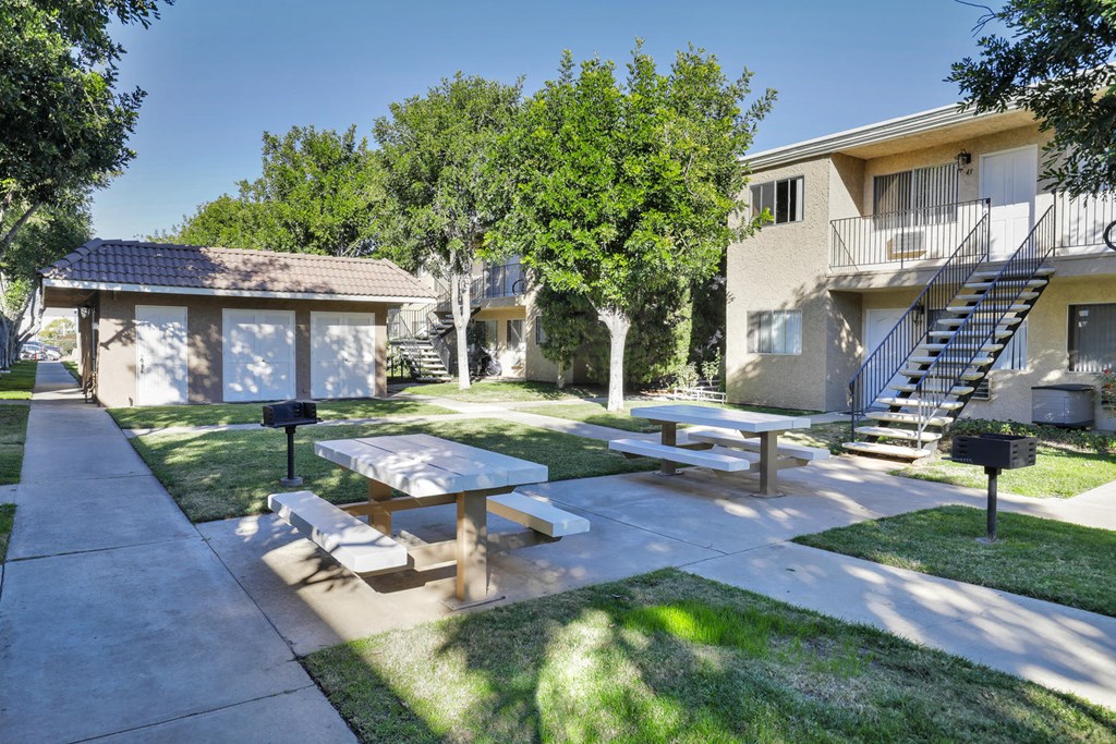 a picnic area with benches and tables in front of an apartment building