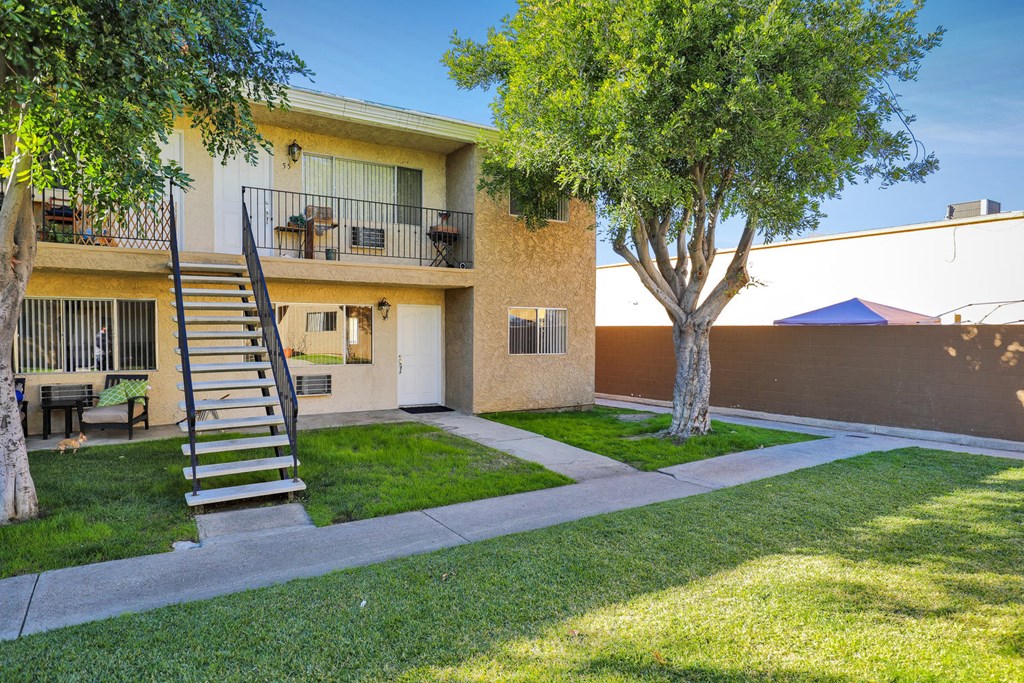 the backyard of an apartment building with a staircase and grass and trees
