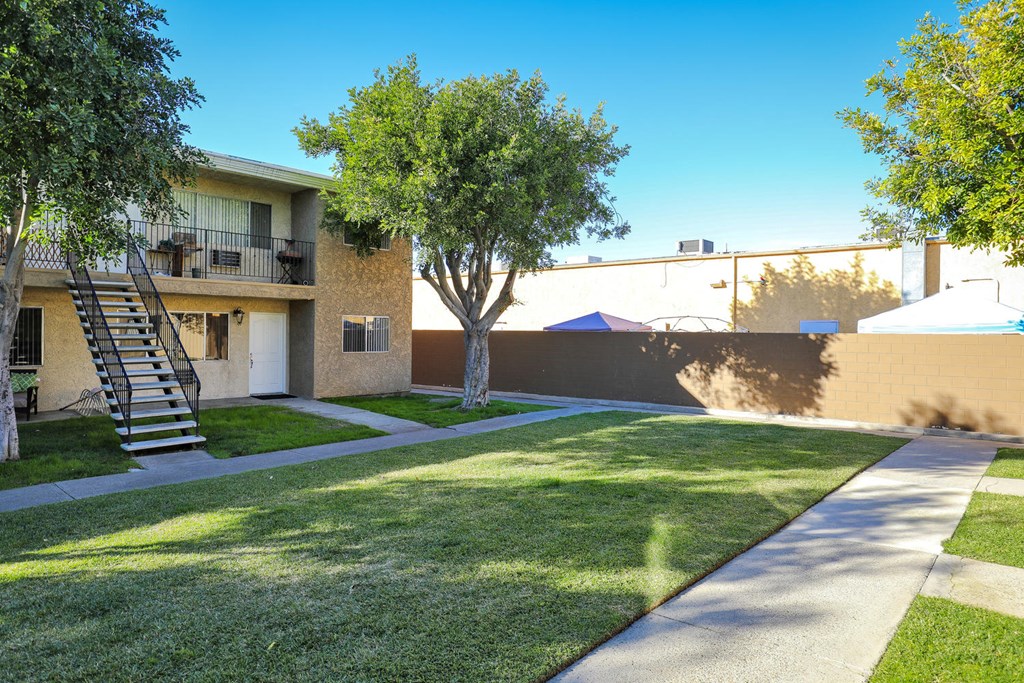 an apartment building with a lawn and trees in front of it