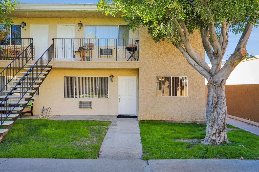 the front of an apartment building with a tree and a sidewalk