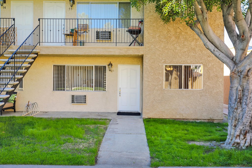 the front of a building with a yard and a white door