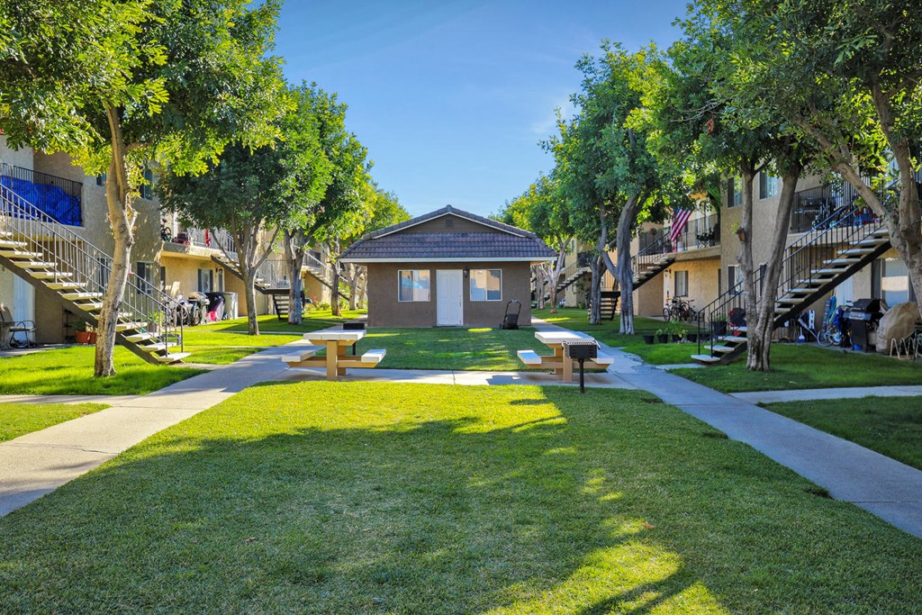 a park with a small building and benches in the grass