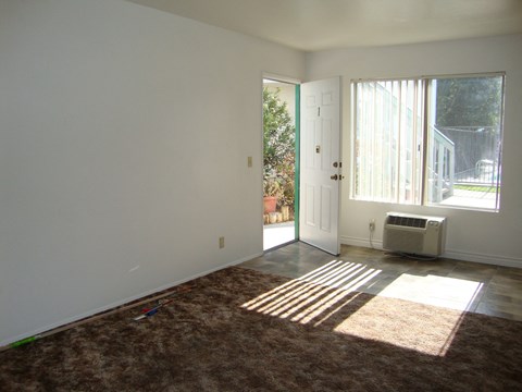 an empty living room with a heater and a door to a patio