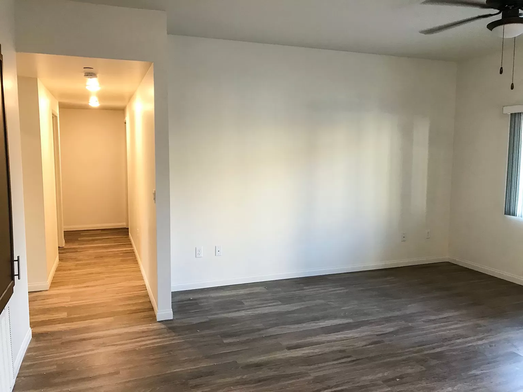 an empty living room with a wood floor and a ceiling fan