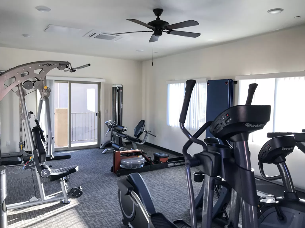 a home gym with exercise equipment and a ceiling fan