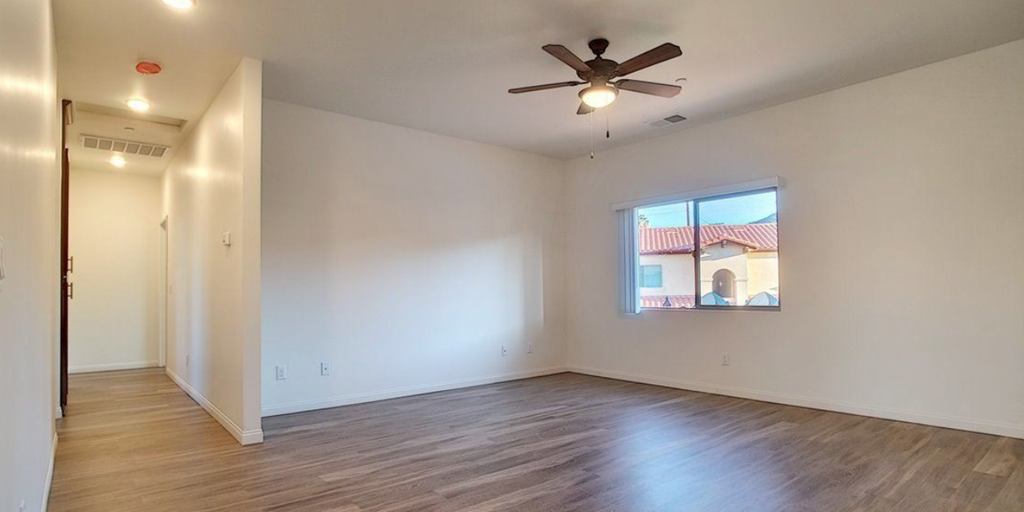 an empty living room with a ceiling fan and a window