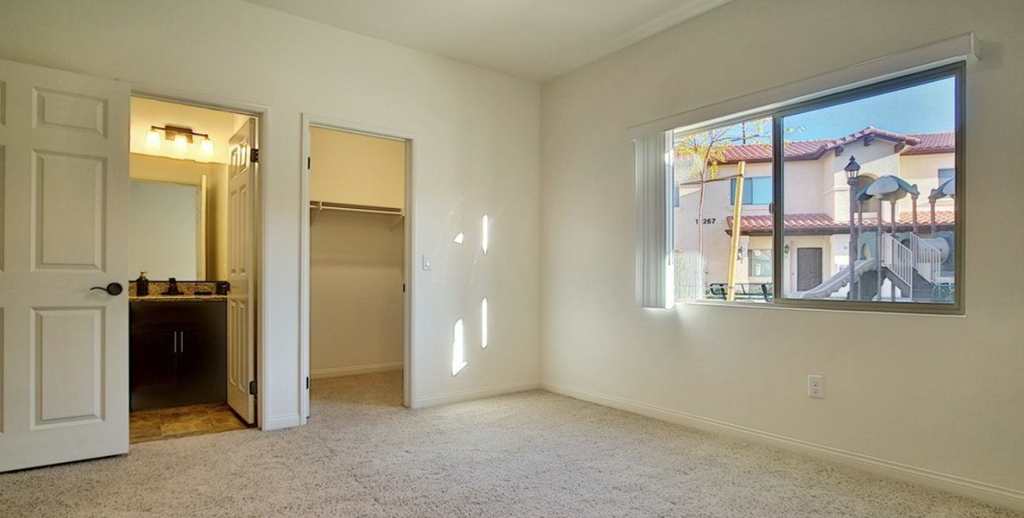 an empty living room with a window and a door to a bathroom