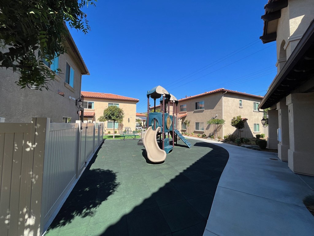 a playground in the middle of a sidewalk between two houses