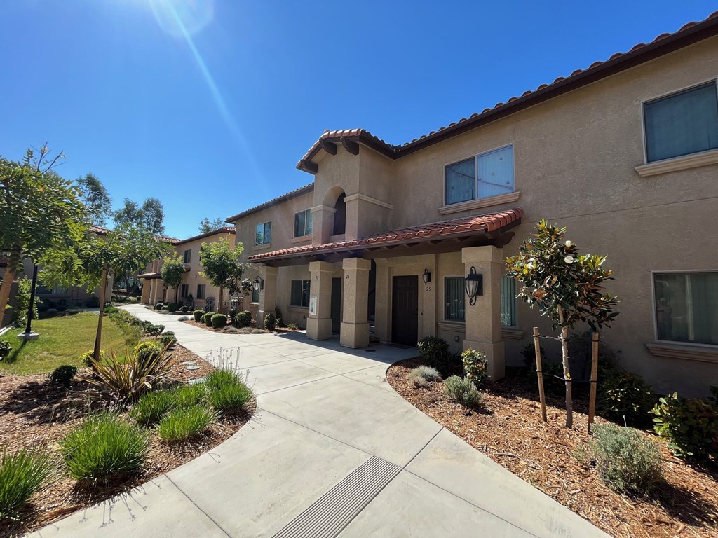 a building with a sidewalk and plants in front of it