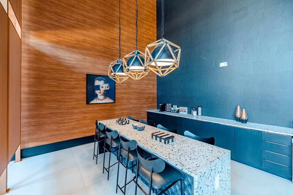 a dining room with a long table and chairs and a blue wall with geometric lamps