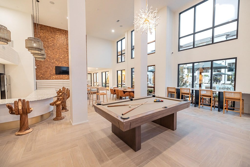 A billiard table is in the middle of a room with a brick wall and a television.