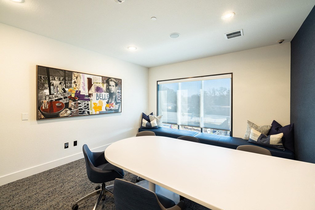 a conference room with a large white table and a window