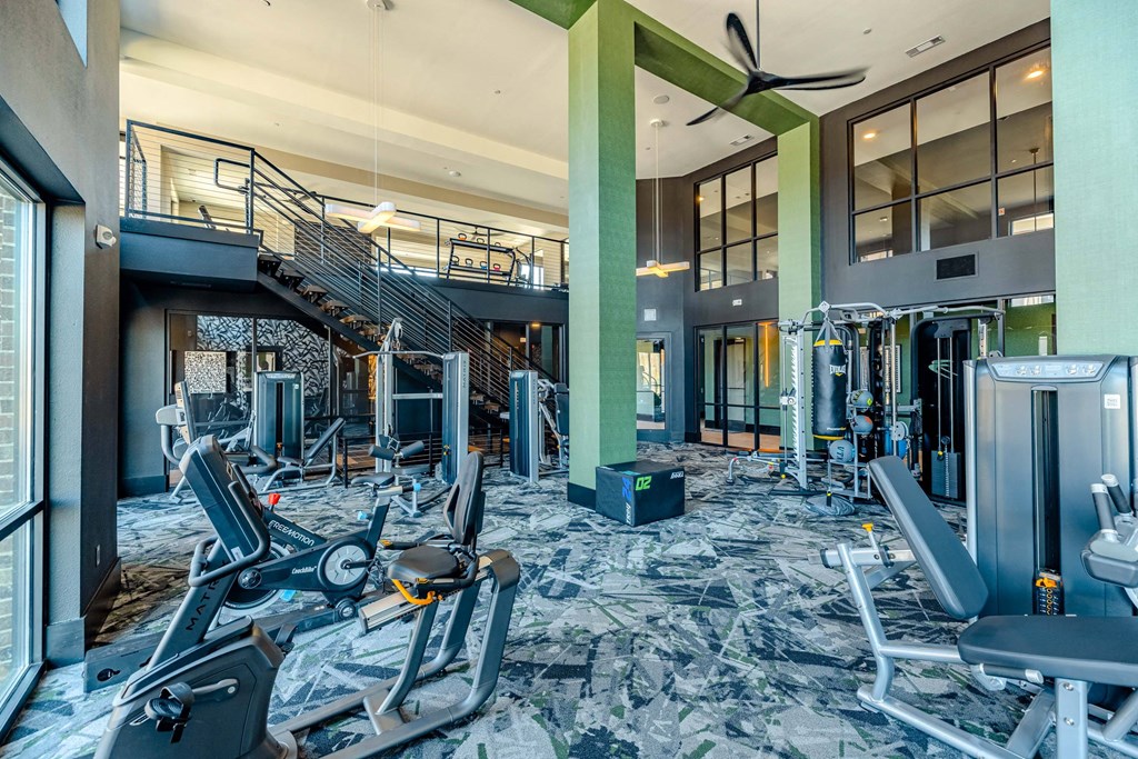 a gym with cardio equipment and a staircase