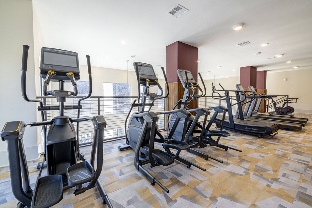 a gym with various cardio equipment on a wooden floor