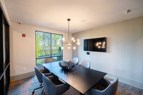 a dining room with a black table and chairs and a tv on the wall