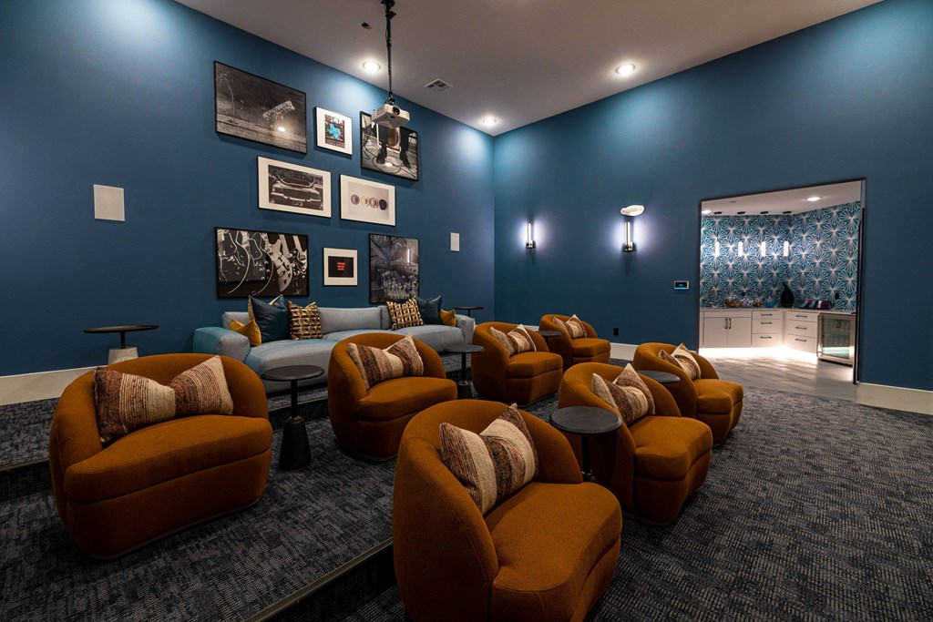 a living room with couches and chairs and a blue wall with pictures