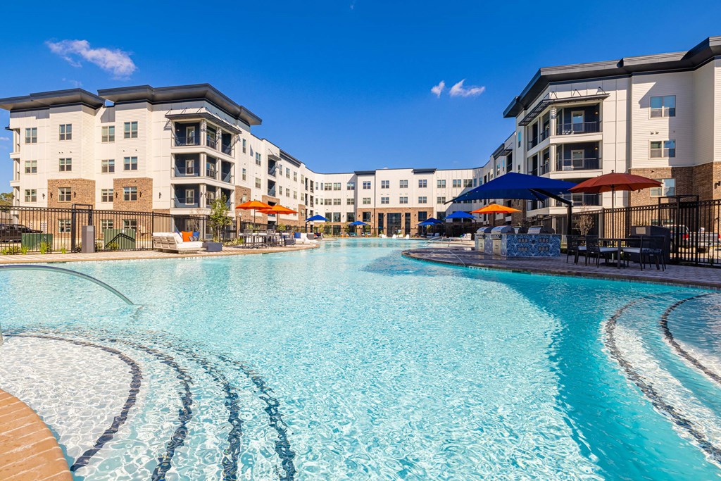 a large swimming pool with apartments in the background