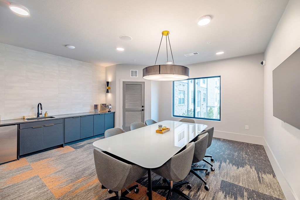 a dining room with a white table and chairs and a kitchen with blue cabinets