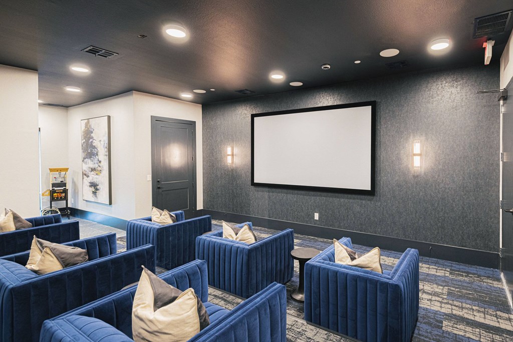 a large screening room with blue couches and a projector screen