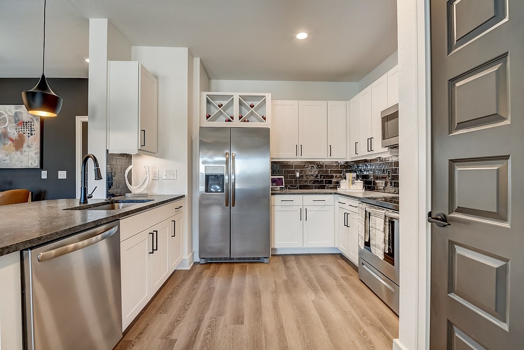 an open kitchen with stainless steel appliances and white cabinets