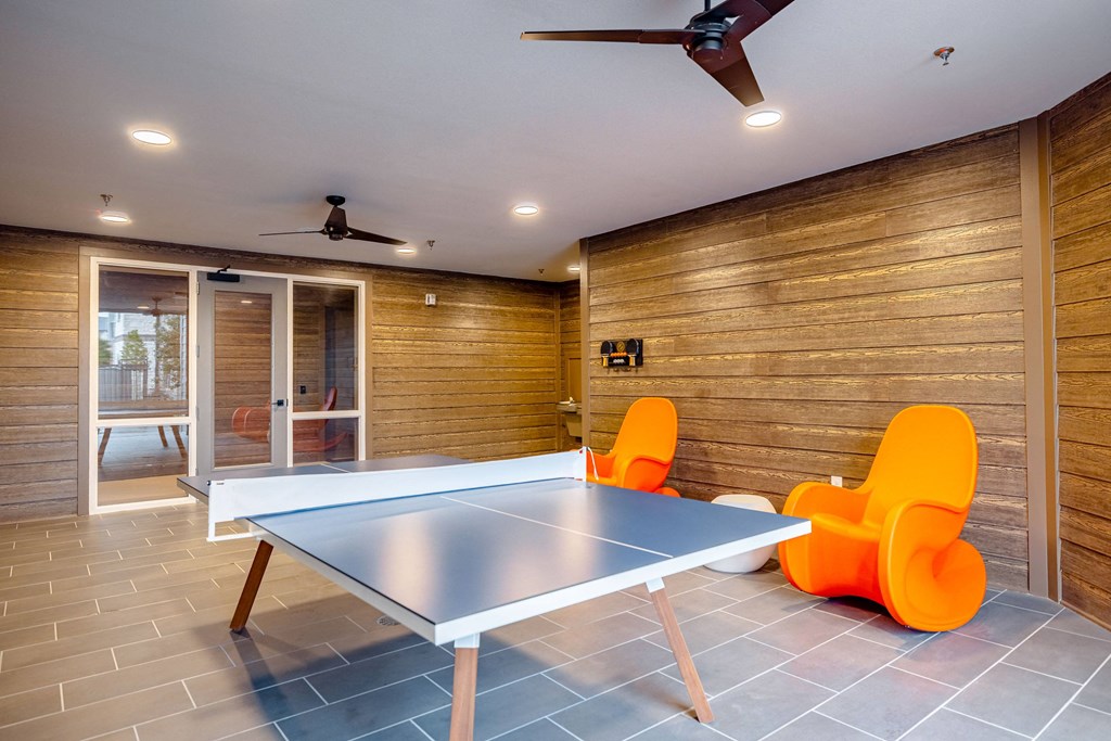a game room with a ping pong table and chairs