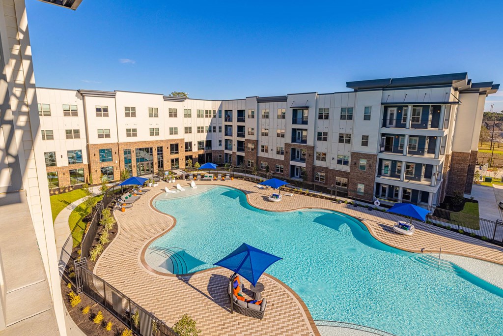 an aerial view of a swimming pool with an apartment building in the background
