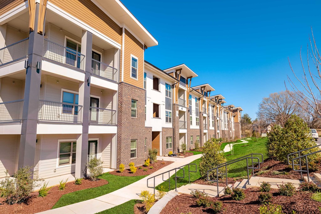 a row of apartment buildings with stairs and grass