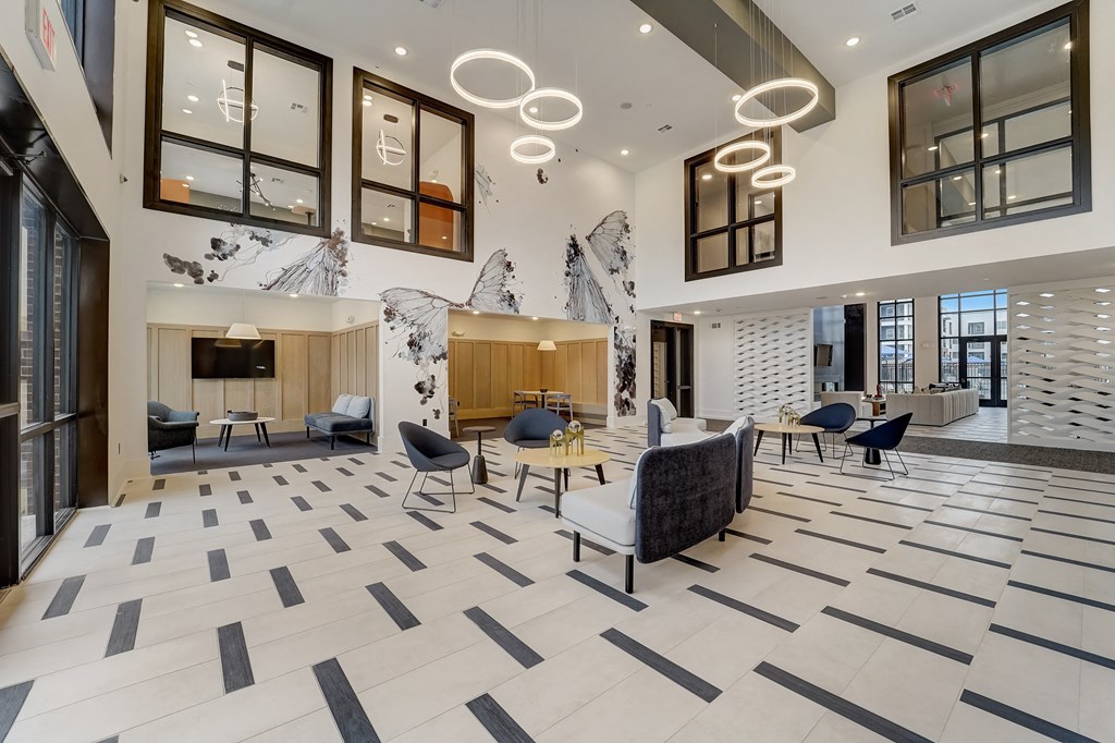 the lobby of a building with chairs and a table and a fireplace
