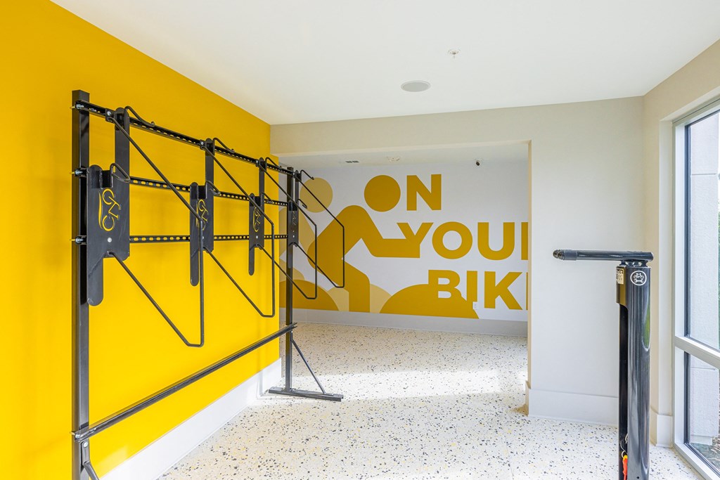 a room with a yellow wall with a bike rack and a sign on the wall