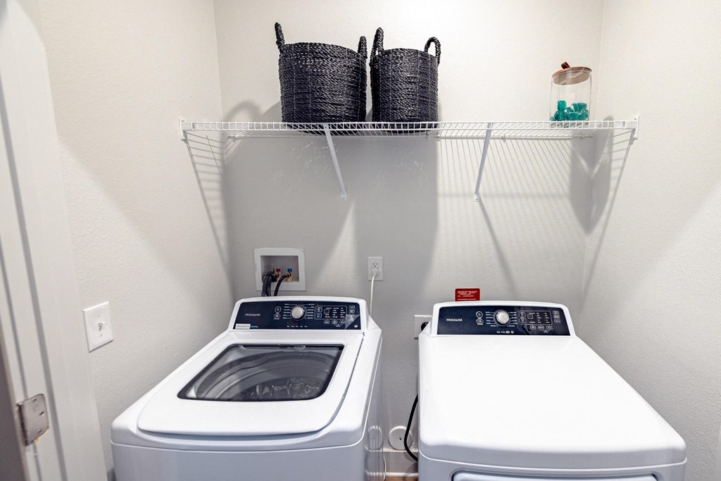 two washing machines in a laundry room with two baskets on top of them