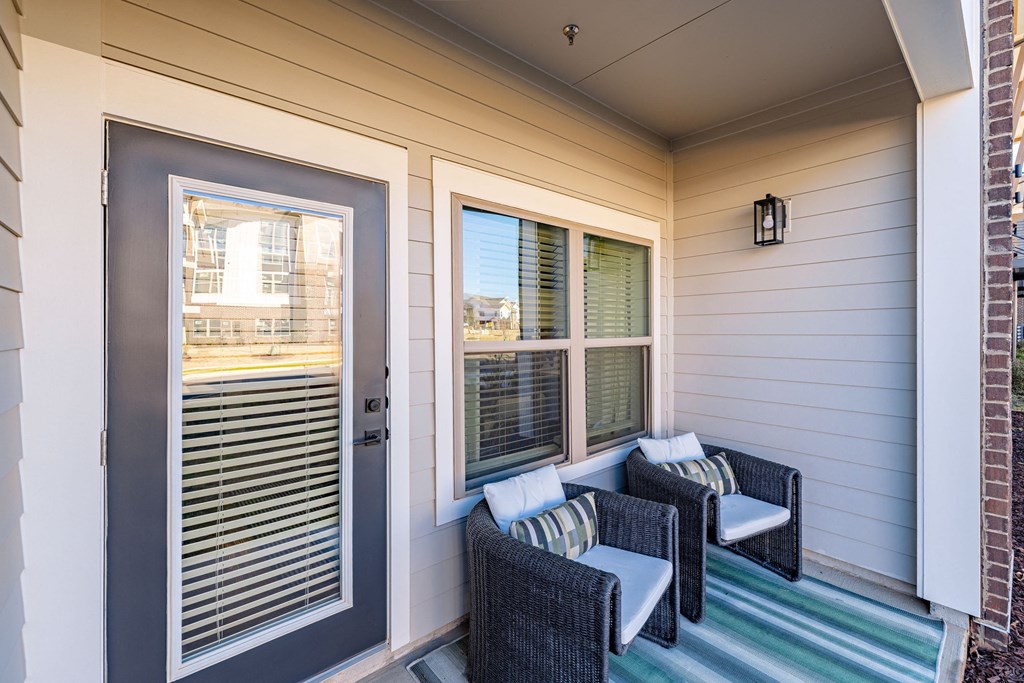 the front porch of a house with wicker furniture and a door